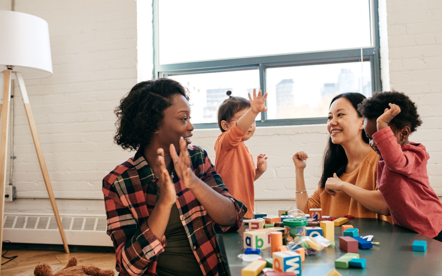 Two moms and their babies clapping and playing with letter blocks